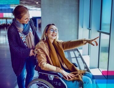 woman in wheelchair pointing out of airport window